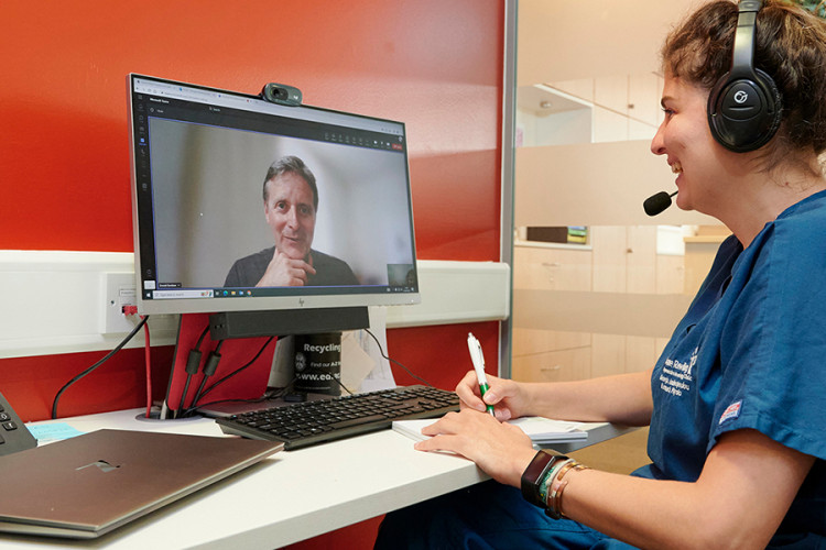 Researcher sitting in a confidential booth carrying out an online consultation with a trial participant.