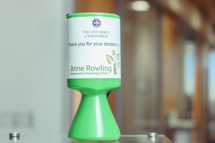 An Anne Rwoling Clinic collection tin in the centre saying 'Thank you for your donations on it'