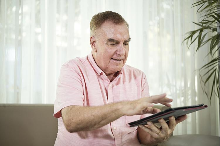 Man in pink short sleeved shirt using a tablet
