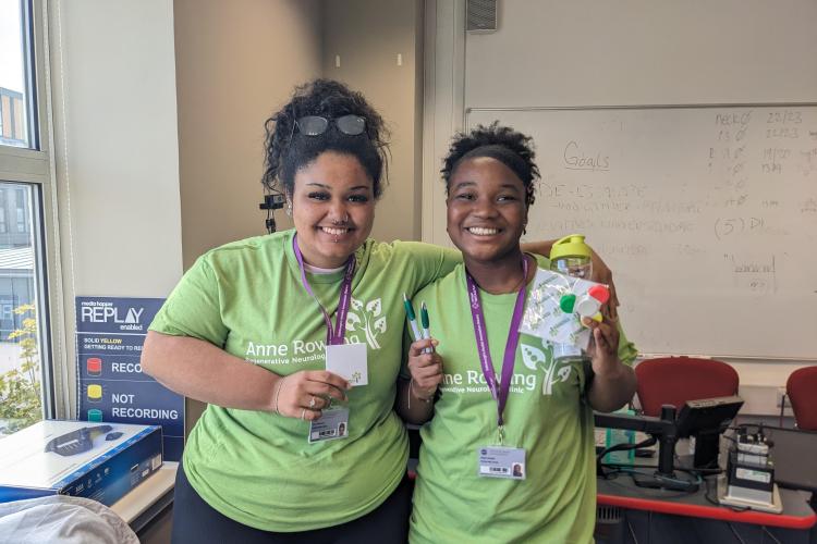 Two of the Edinburgh BioQuarter School Interns wearing Anne Rowling Clinic t-shirts and holding branded merchandise