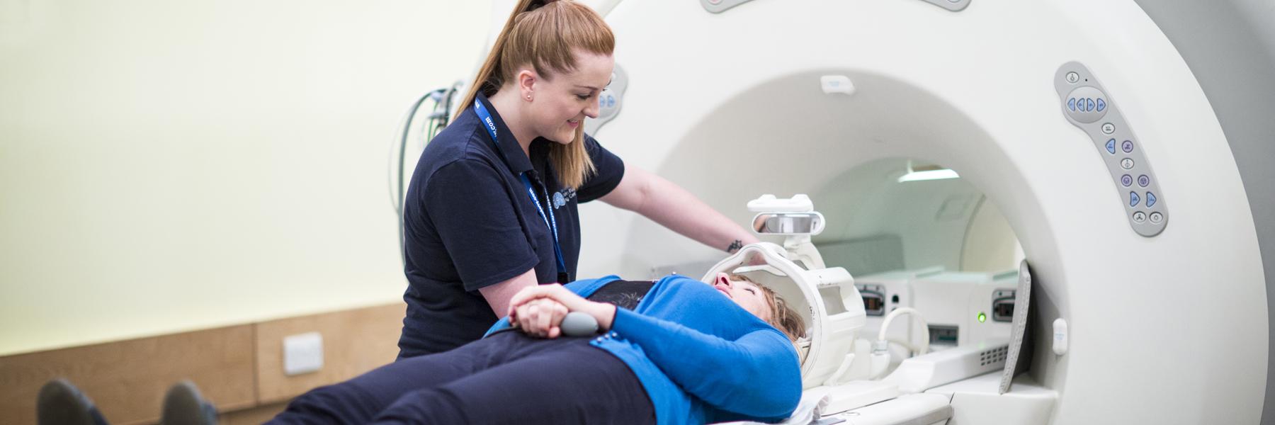 A radiographer helping a person into an MRI machine