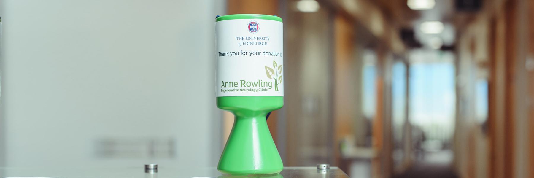 An Anne Rwoling Clinic collection tin in the centre saying 'Thank you for your donations on it'