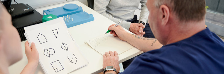 a patient performing a cognitive shape drawing test with paper and pen