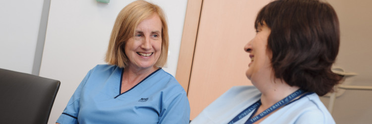 Two nurses sat smiling and chatting with each other