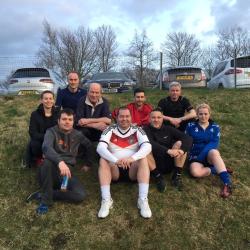 Jamie Smith and friends sat on a grass hill wearing sports clothes.