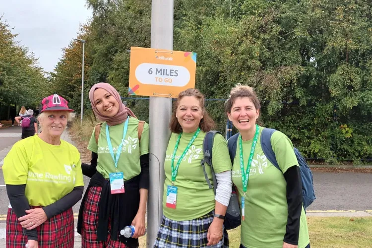 A picture of the Anne Rowling Clinic 2023 Kiltwalk Team at the 6 mile post. Everyone is smiling and wearing Clinic t-shirts and tartan.