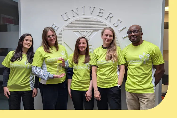 A picture of the Edinburgh MS Imaging Research Team in Anne Rowling Clinic branded green shirts, the team are standing outside the Clinic building with the University of Edinburgh's logo behind them. 