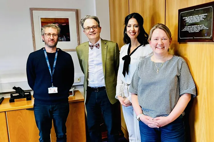 Four people standing in a seminar room. Left to right is Dr Axel Montagne [internal examiner], Prof Giampetro Schiavo [external examiner], Dr Maria Stavrou [PhD candidate], Prof Selina Wray [external examiner]. The photo was taken after Maria's "viva voce" (oral) examination of her PhD.