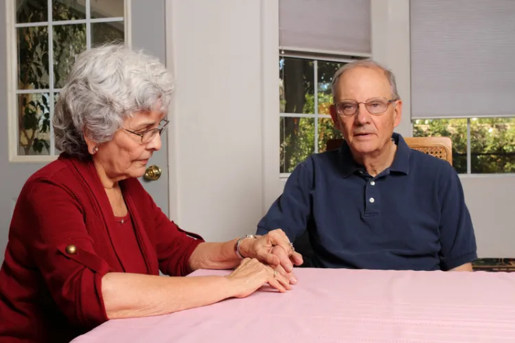 Older aged couple holding hands while sitting at a table